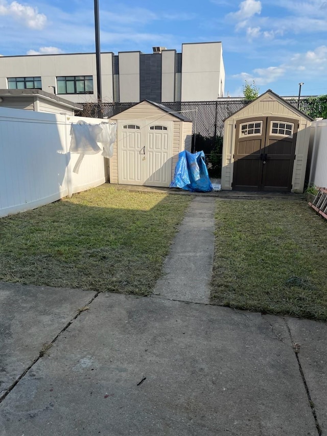 view of yard with a fenced backyard, an outbuilding, and a storage unit