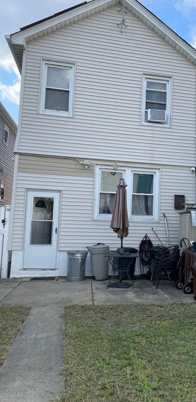 back of property featuring cooling unit, a yard, and a patio