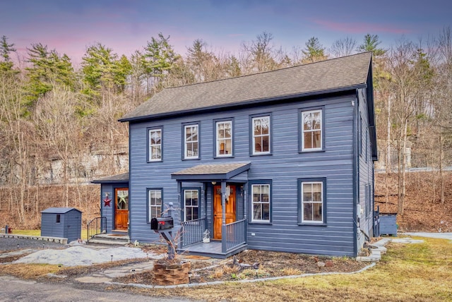 view of front of home featuring an outbuilding, a shed, and a shingled roof