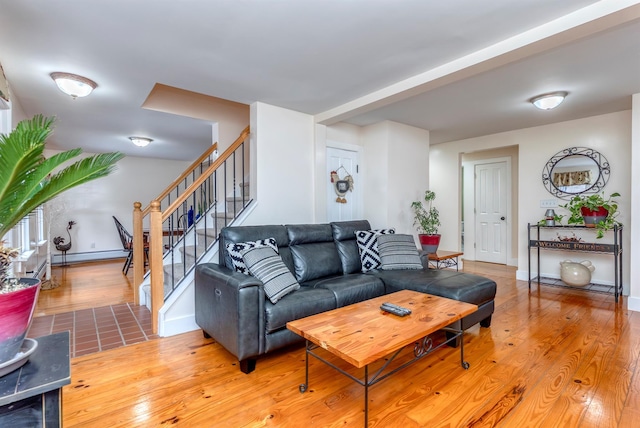 living area featuring a baseboard heating unit, stairs, baseboards, and wood finished floors