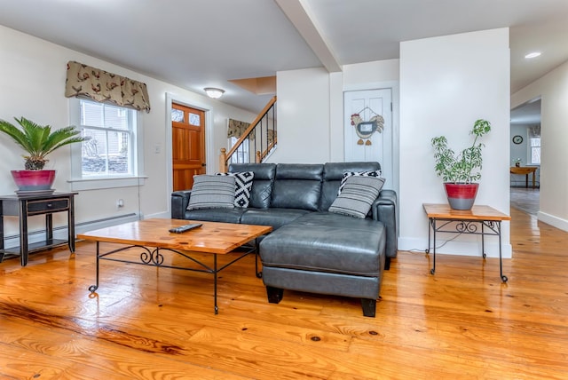 living area featuring stairway, baseboards, light wood-style floors, and a baseboard radiator