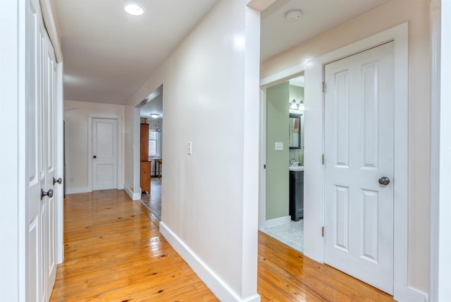 hallway featuring baseboards and light wood finished floors