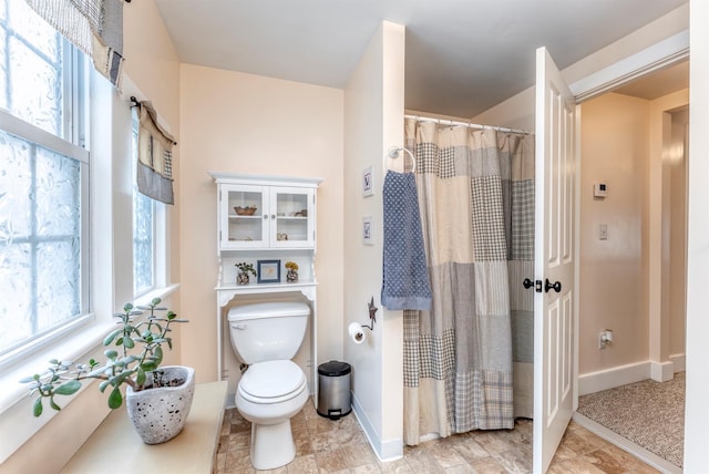 bathroom featuring a shower with curtain, toilet, and baseboards
