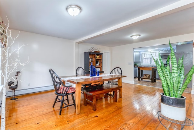 dining room with light wood-type flooring, a baseboard heating unit, and baseboards