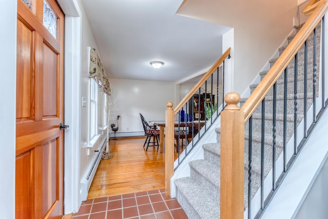 entryway with stairway, dark tile patterned flooring, baseboard heating, a baseboard heating unit, and a wealth of natural light