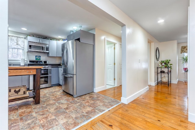 kitchen with recessed lighting, stainless steel appliances, baseboards, and light wood-style flooring