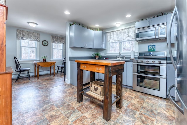 kitchen with a sink, a baseboard heating unit, recessed lighting, stainless steel appliances, and baseboards