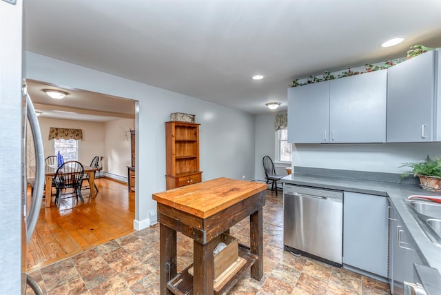 kitchen featuring recessed lighting, stainless steel appliances, stone finish flooring, and baseboards
