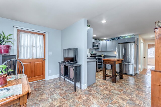 kitchen featuring stone finish floor, recessed lighting, baseboards, and appliances with stainless steel finishes