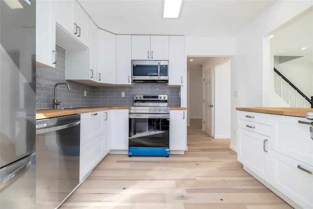 181 Vernon Valley Rd, East Northport, NY 11731 - kitchen featuring butcher block counters, stainless steel appliances, a sink, light wood-style flooring, and tasteful backsplash