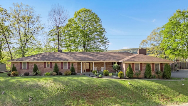 single story home featuring a chimney, a front lawn, and brick siding