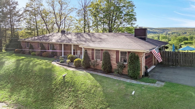 ranch-style house with fence, a front yard, a chimney, brick siding, and an attached garage