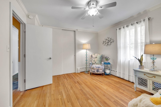 sitting room with crown molding, baseboard heating, a ceiling fan, and wood finished floors