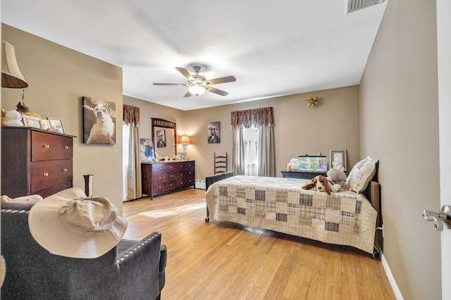 bedroom featuring visible vents, baseboards, light wood finished floors, and a baseboard heating unit