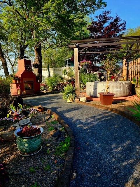view of yard with fence, a patio, and a warm lit fireplace