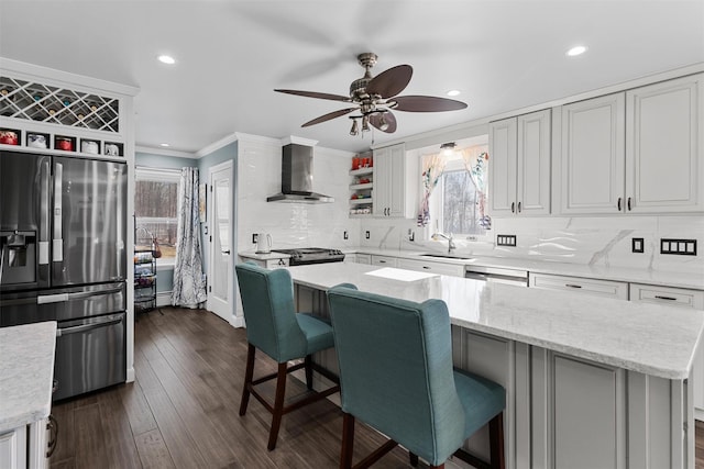 kitchen with wall chimney range hood, open shelves, a ceiling fan, fridge with ice dispenser, and ornamental molding