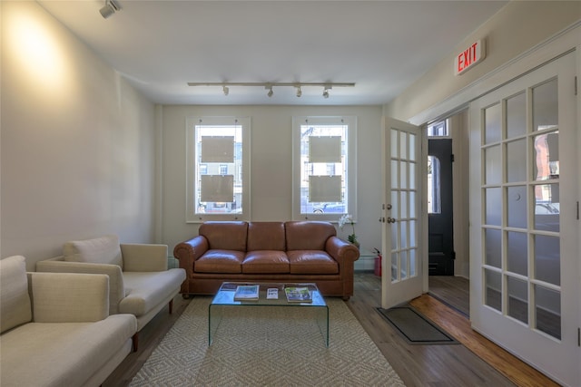 living area with a baseboard radiator, wood finished floors, rail lighting, and french doors