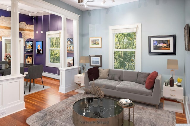 living area featuring decorative columns, a baseboard radiator, and wood finished floors