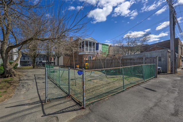 view of front of home with a gate, fence, a sunroom, and brick siding