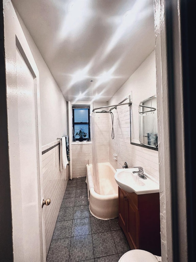 full bath featuring tile patterned floors, shower / bath combination with curtain, vanity, tile walls, and wainscoting