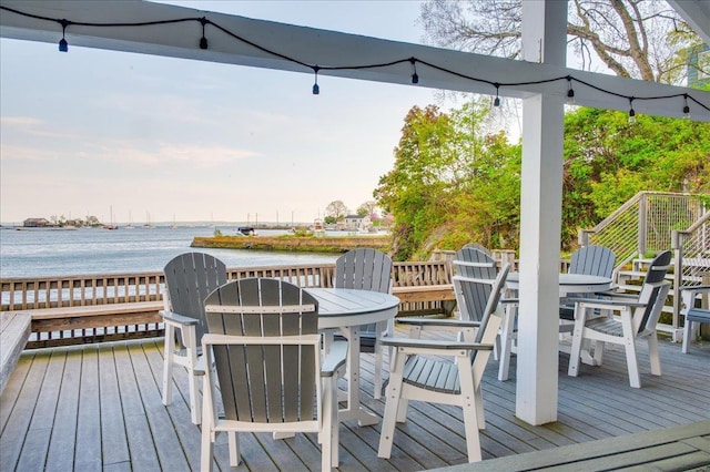 wooden deck featuring a water view and outdoor dining space
