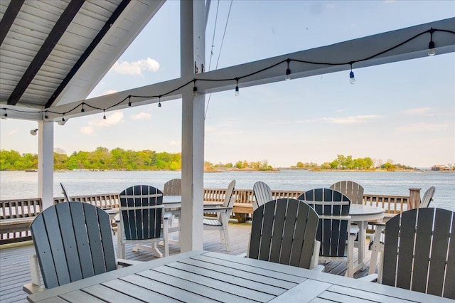 wooden deck featuring outdoor dining area and a water view