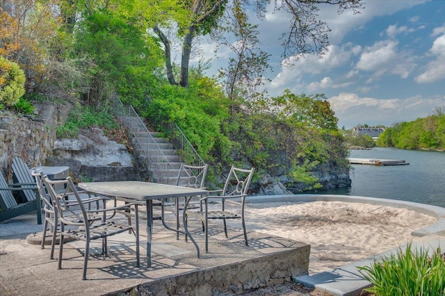 view of patio with stairway, a water view, a floating dock, and outdoor dining space
