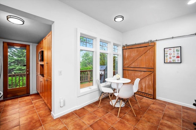 tiled dining area with a barn door, baseboards, and a healthy amount of sunlight