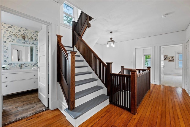staircase featuring an inviting chandelier and hardwood / wood-style flooring