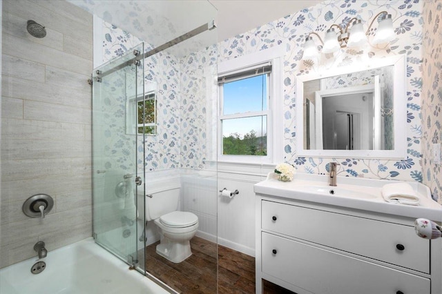 full bathroom with toilet, wood finished floors, vanity, enclosed tub / shower combo, and wallpapered walls