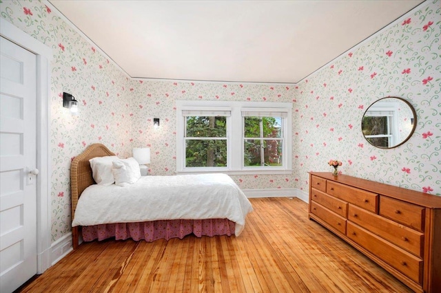 bedroom featuring baseboards, light wood finished floors, and wallpapered walls