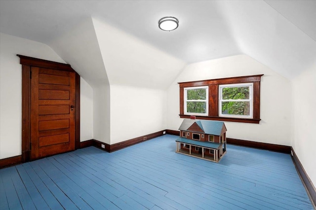 additional living space with dark wood finished floors, baseboards, and lofted ceiling