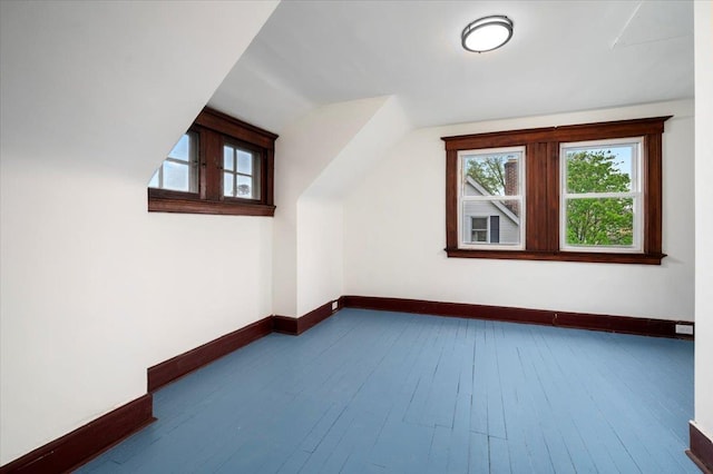 additional living space with baseboards, hardwood / wood-style floors, and a healthy amount of sunlight