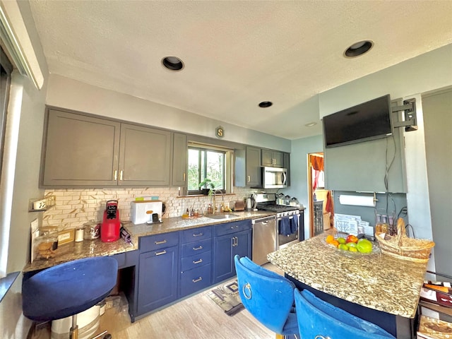15 Highland Ave, Chestnut Ridge, NY 10977 - kitchen featuring a sink, stainless steel appliances, light wood-style floors, backsplash, and a textured ceiling