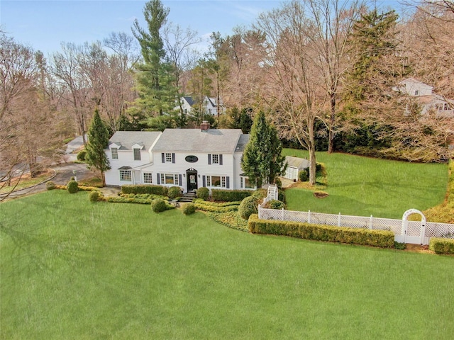 view of front of property featuring a front lawn, a chimney, and fence private yard