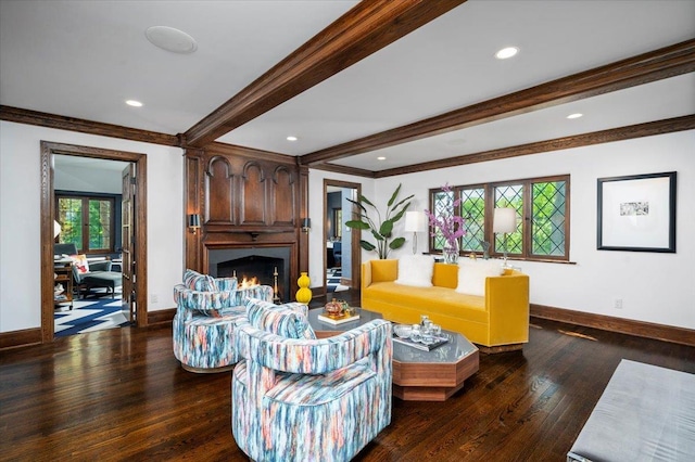 living area with crown molding, baseboards, wood finished floors, beamed ceiling, and a lit fireplace