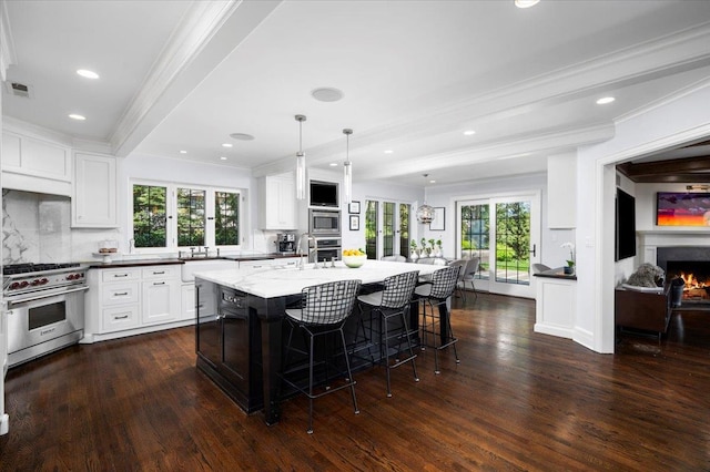 kitchen featuring appliances with stainless steel finishes, a breakfast bar, backsplash, a lit fireplace, and ornamental molding