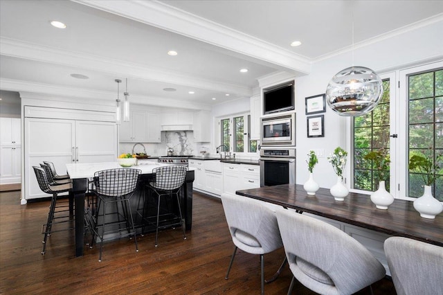 dining room with dark wood-type flooring, ornamental molding, and recessed lighting