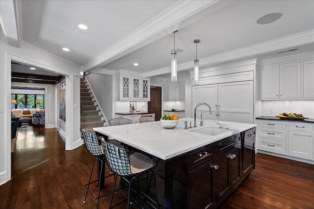 kitchen with a kitchen breakfast bar, a sink, ornamental molding, recessed lighting, and white cabinetry