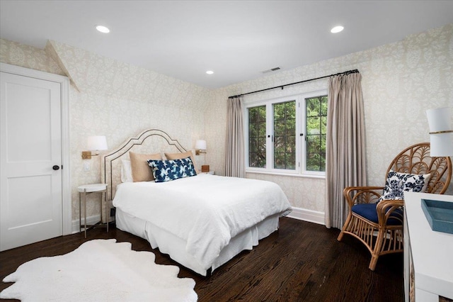 bedroom featuring visible vents, baseboards, dark wood-style floors, and wallpapered walls