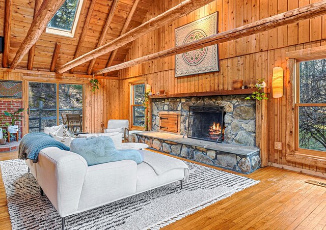 79 Torre Rock Rd, Red Hook, NY 12571 - living room featuring wood walls, a fireplace, healthy amount of natural light, light wood-style flooring, and high vaulted ceiling