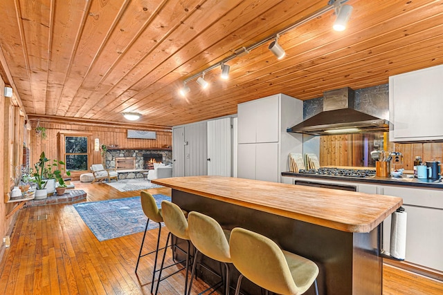 79 Torre Rock Rd, Red Hook, NY 12571 - kitchen with wall chimney range hood, rail lighting, butcher block counters, white cabinetry, and wood walls