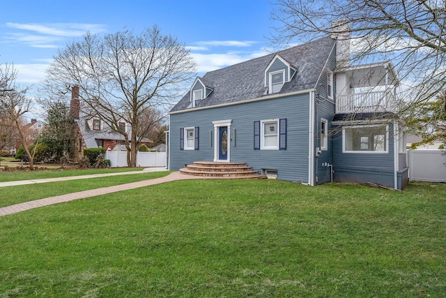 view of front of house featuring a front lawn, a balcony, a chimney, and fence