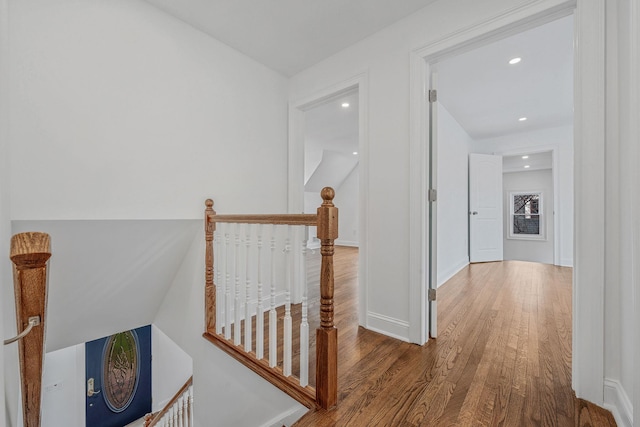 hall featuring baseboards, wood finished floors, an upstairs landing, and recessed lighting