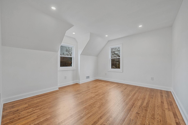 additional living space featuring light wood finished floors, lofted ceiling, baseboards, visible vents, and recessed lighting