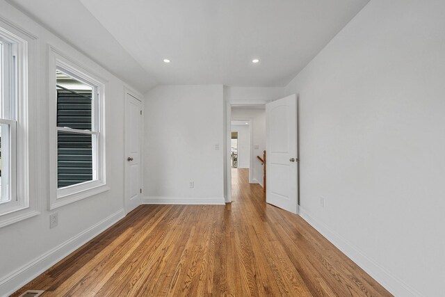 spare room featuring recessed lighting, a wealth of natural light, baseboards, and wood finished floors