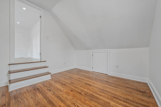 bonus room with baseboards, lofted ceiling, and wood finished floors