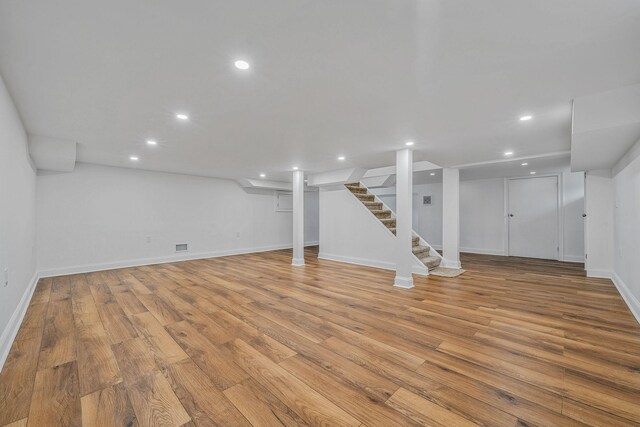 finished basement featuring stairs, light wood-style floors, and recessed lighting