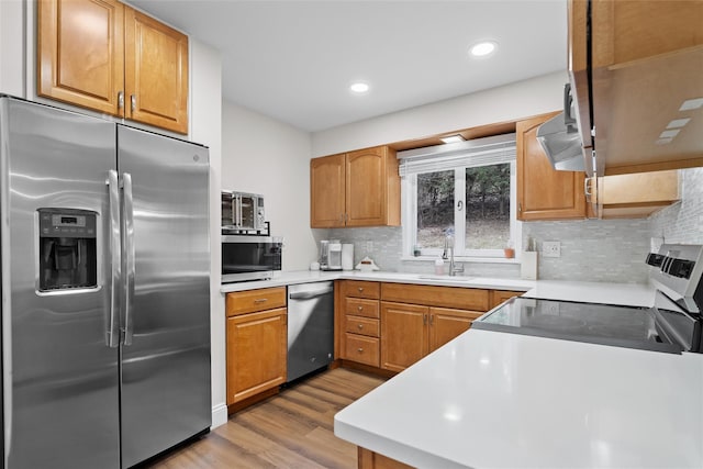 kitchen featuring decorative backsplash, a sink, stainless steel appliances, and light wood-style flooring
