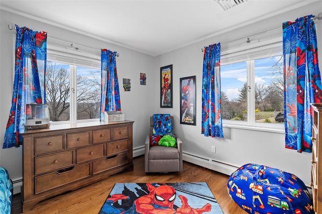 bedroom with a baseboard radiator, wood finished floors, and visible vents